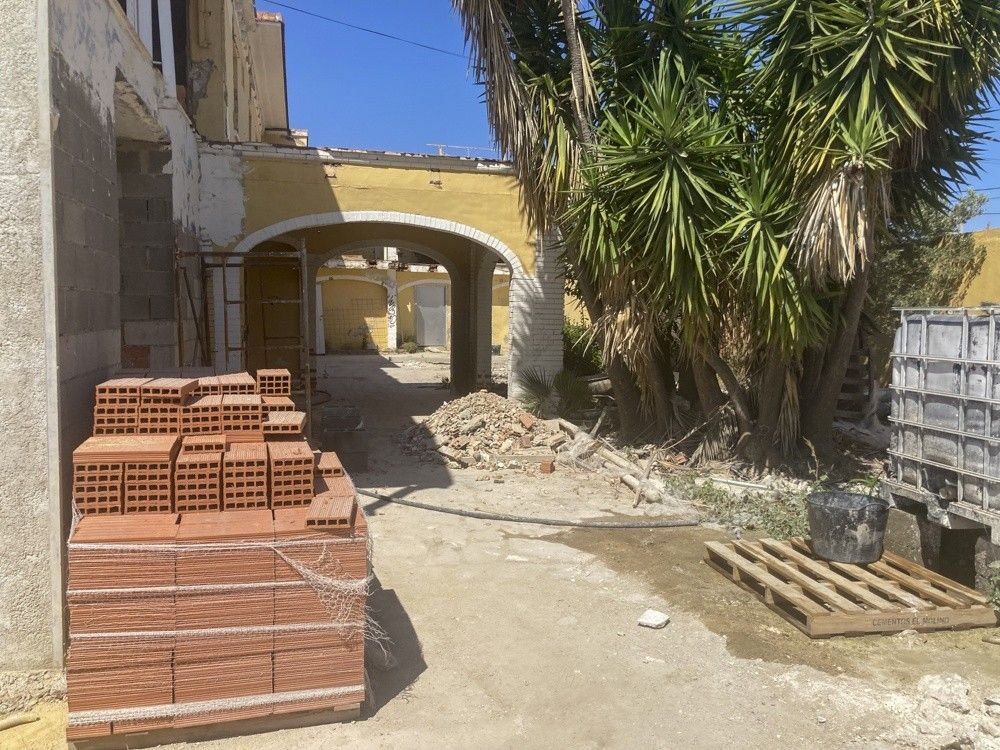 Acopio de ladrillo y acceso con arcos durante la obra