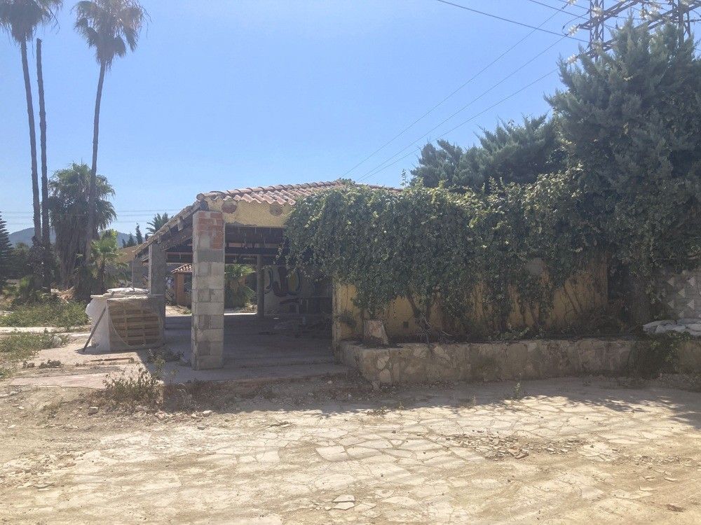 Edificación auxiliar cubierta de vegetación antes de la rehabilitación
