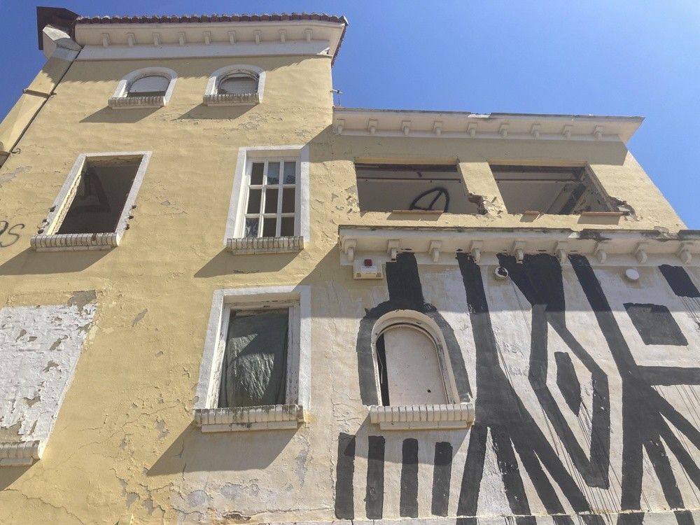 Fachada con ventanas tapiadas y pintadas antes de rehabilitar la casa