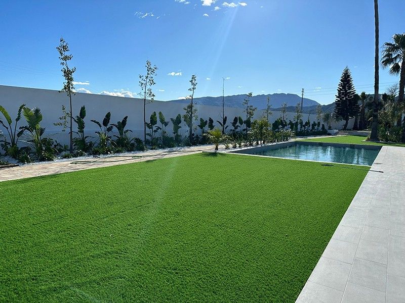 Piscina y jardín de césped artificial con montañas al fondo