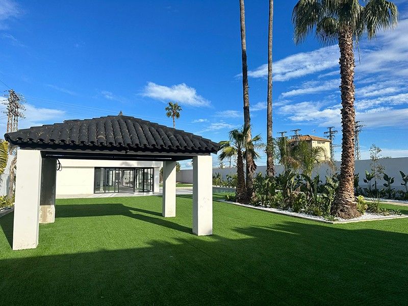 Porche con cubierta de teja sobre pilares blancos y jardín de césped