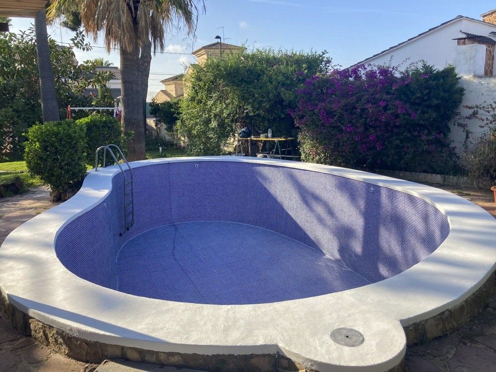 Piscina de formas curvas con gresite azul y coronación blanca en Torrent