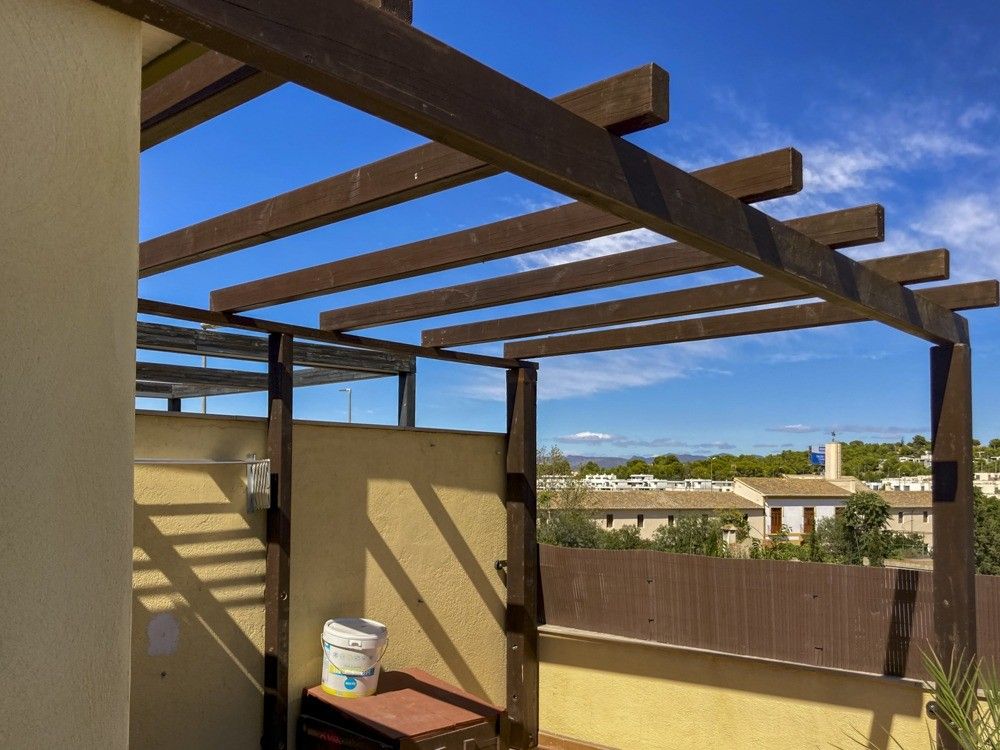 Pérgola fija de madera oscura en terraza de chalet en San Antonio de Benagéber